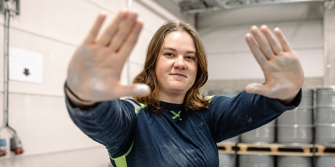 Maja Melander visar sina händer som har aluminiumpulver på sig. Hon tittar rakt in i kameran.