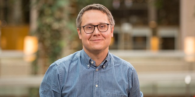 EU-parlamentarikern Johan Danielsson i blå skjorta framför en byggnad.