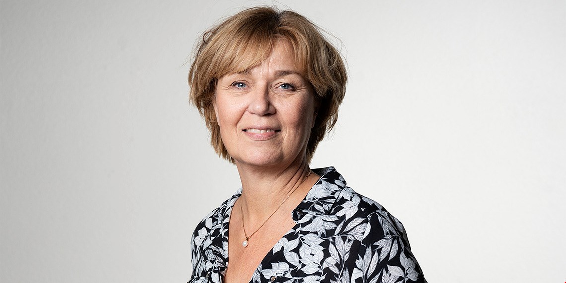 Porträtt av Annika Nilsson, IF Metall, i mönstrad blus framför en vit fond.