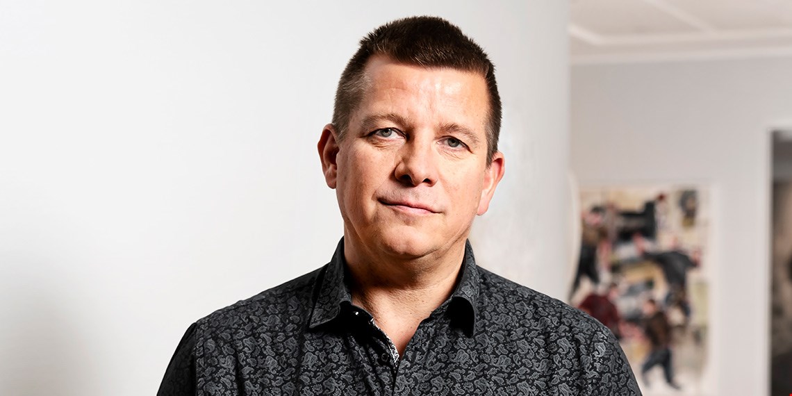 Person i mönstrad skjorta framför ljus vägg.