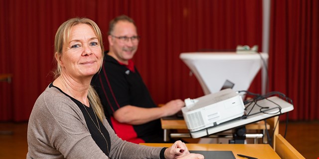 Två personer med en projektor mellan sig.