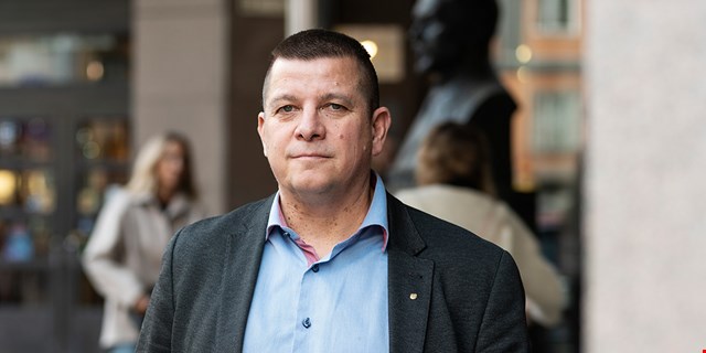IF Metalls avtalssekreterare i ljusblå skjorta och kavaj framför en suddig stadsmiljö.