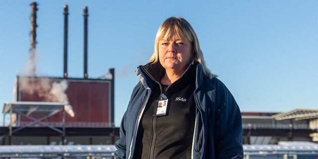 Person med arbetskläder utanför industri.