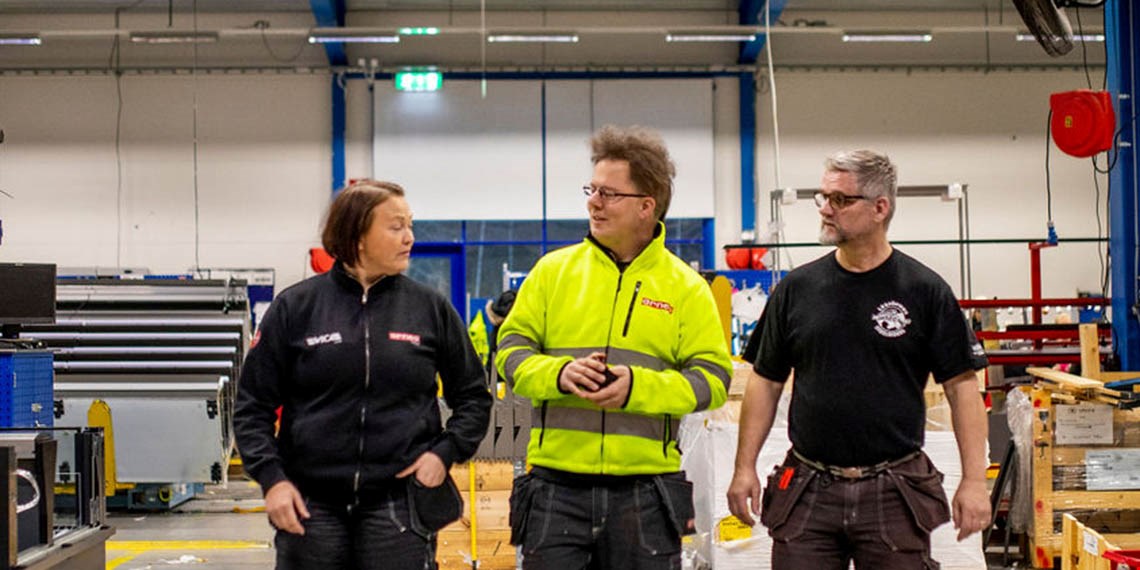 Foto på Martina Holmkvist Lundström, Christoffer A Karlsson och Roland Magnil som går och samtalar i industrimiljö