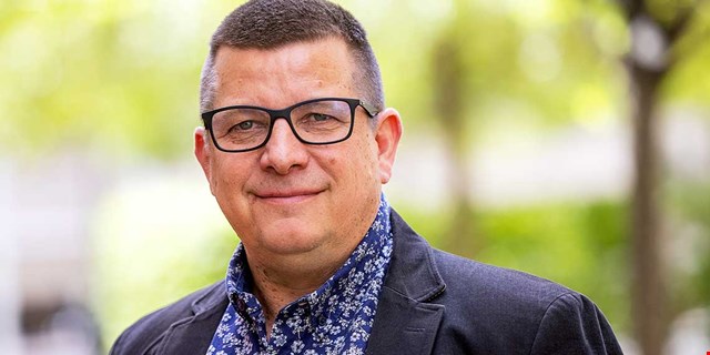 Porträtt av Veli-Pekka Säikkälä utomhus med grön bakgrund.